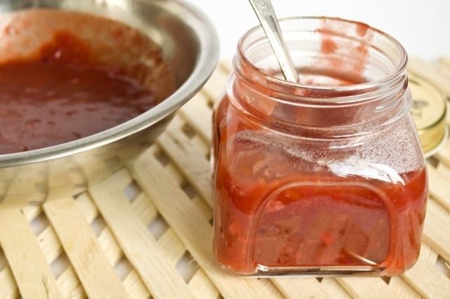 Перекладываем соус ткемали с кусочками овощей в банки