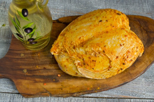 Поливаем куриную грудку растительным маслом и растираем специи по ней