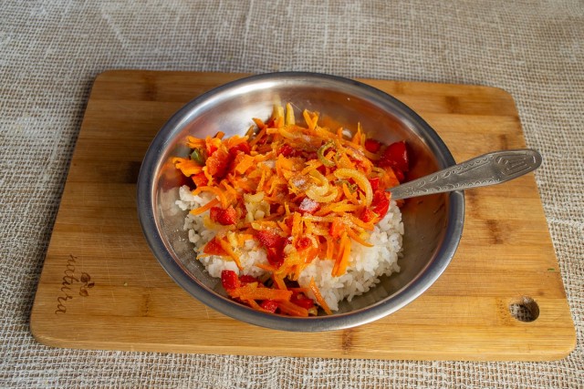Смешиваем варёный рис с овощами, посыпаем молотым перцем, солим по вкусу и тщательно перемешиваем
