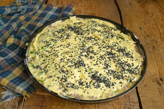 Посыпаем пирог зернышками кунжута. Ставим форму в разогретый духовой шкаф