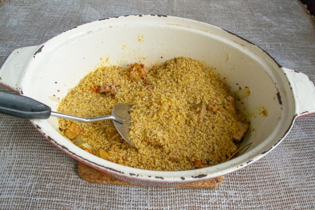 Насыпаем в жаровню булгур, рассыпаем его по мясу ровным слоем