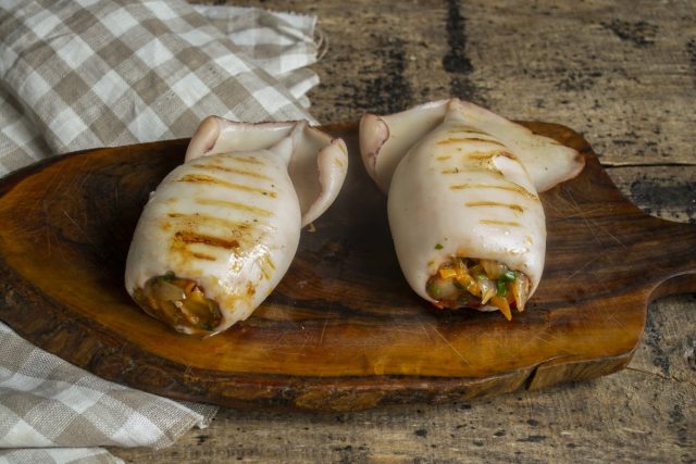 Подаём кальмары, фаршированные овощами и сыром, на стол тёплыми или холодными