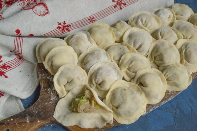 Лепим пельмени и укладываем на доску, посыпанную мукой