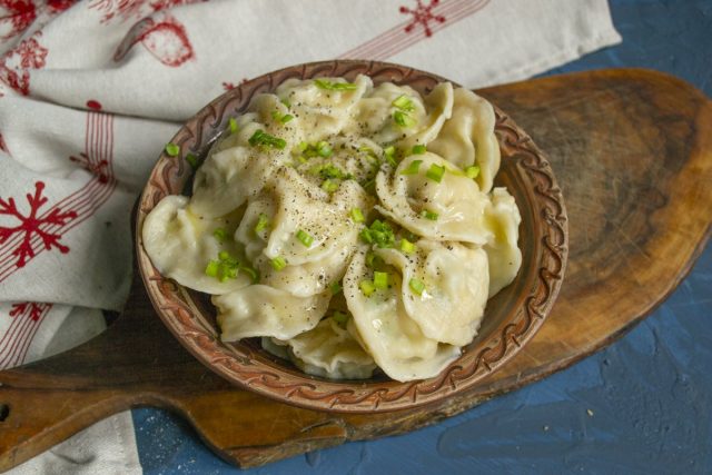 Поливаем пельмени растопленным маслом, посыпаем луком и перчим