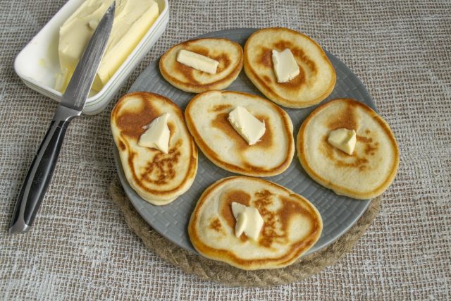 На каждый горячий оладушек кладём небольшой кусочек сливочного масла