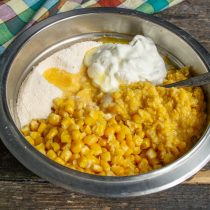 В миску выкладываем кукурузные зёрна, баночку измельченной кукурузы, добавляем сухие ингредиенты и сметану