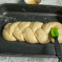 Аккуратно смазываем расстоявшуюся халу взбитым яйцом