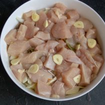 Выкладываем нарезанное кубиками куриное филе и пластинки чеснока