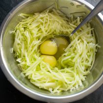 Натираем кабачки на крупной терке, разбиваем куриные яйца, солим