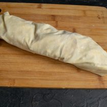 Заворачиваем короткие края на начинку и аккуратно сворачиваем штрудель