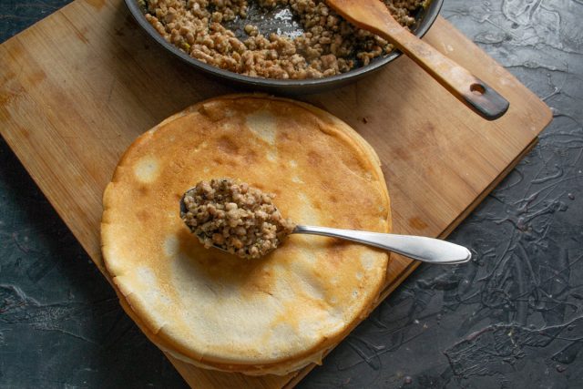 На середину блина кладём обжаренный фарш с луком и сворачиваем конверты-трубочки