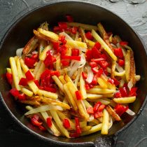 Шумовкой перекладываем жареную картошку в сковороду, посыпаем нарезанным перцем