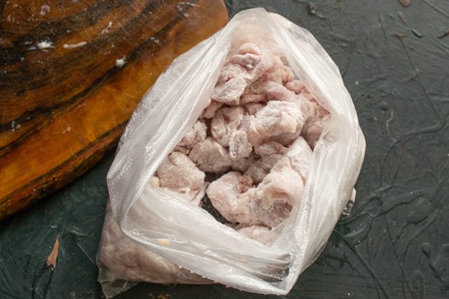 В пакет насыпаем пшеничную муку и кладём курицу. Завязываем мешок узлом и встряхиваем, пока кусочки курицы не покроет панировка