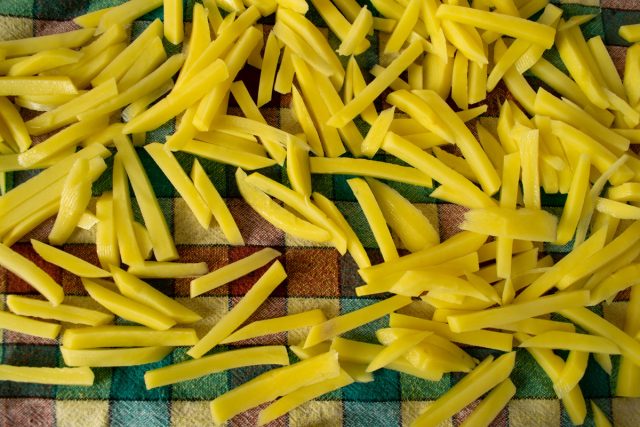 Картофель чистим от кожуры, нарезаем брусочками. Нарезанную картошку заливаем холодной водой. Тщательно промываем картофель, смываем крахмал. Затем высушиваем наши брусочки на полотенце