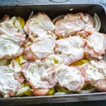 На лук выкладываем куриные бедра кожей к верху. Кладём кусочки курицы