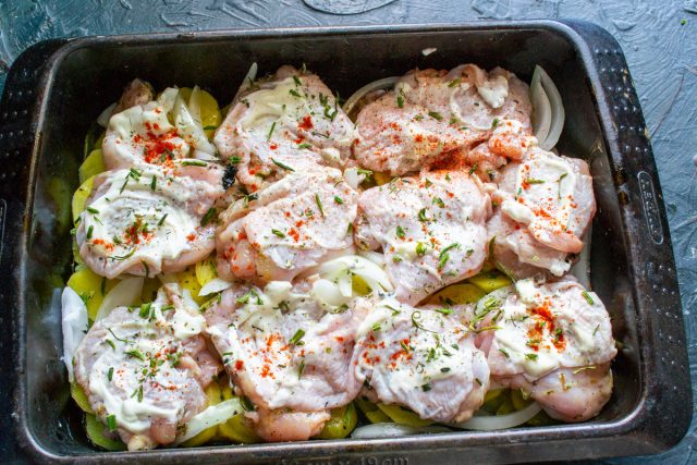 Смазываем курицу густой жирной сметаной. Посыпаем сушеной петрушкой, черным перцем и молотой сладкой паприкой