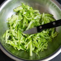 Раннюю капусту шинкуем узкими полосками, посыпаем щепоткой соли и разминаем руками