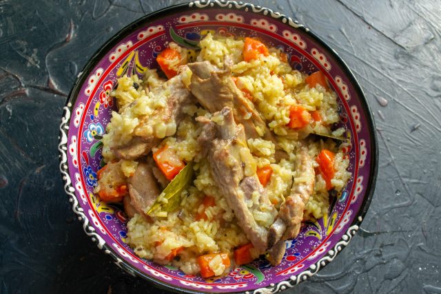 Выкладываем свиные ребрышки с рисом в глубокое блюдо горкой и подаём на стол!