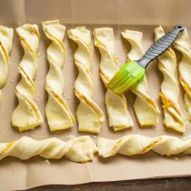 Смазываем сырные палочки молочно-яичной смесью. Смазываем сырные палочки молочно-яичной смесью.