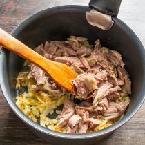 Нежирное вареное мясо разрываем на волокна, бросаем в кастрюлю к луку.