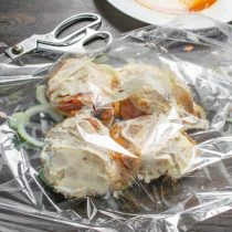 На лук кладем маринованные в меду куриные бедра, смазываем сверху майонезом.