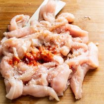 Куриную грудку нарезаем поперек волокон длинными узкими полосками.