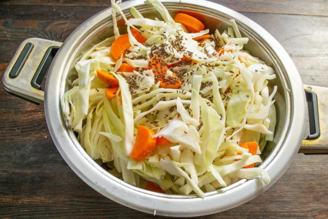 Кладем капусту с морковкой в большую ёмкость, насыпаем тмин.