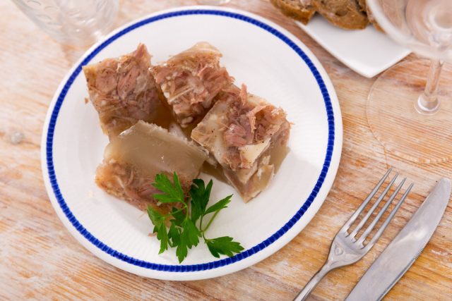 Холодец в глубокой тарелке с хреном и горчицей. Желе с кусочками мяса, которое готовили часами и выносили на балкон остывать. Старомодное, но родное блюдо. Холодец в глубокой тарелке с хреном и горчицей. Желе с кусочками мяса, которое готовили часами и выносили на балкон остывать. Старомодное, но родное блюдо.