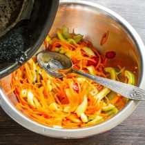 Кипящее масло с кунжутом вливаем в миску с овощами.
