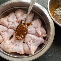 Кладём подготовленные крылышки в миску, заливаем маринадом.