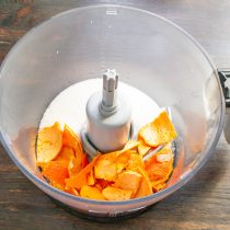 В чашу блендера устанавливаем насадку нож, насыпаем сахарный песок, добавляем нарезанную мандариновую кожуру.