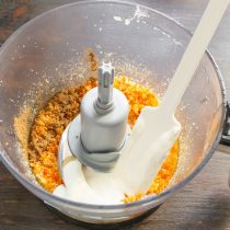 Добавляем в чашу жирную сметану, разбиваем куриное яйцо, выжимаем сок из одного мандарина.