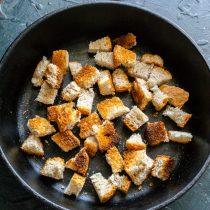 Высыпаем нарезанный хлеб на противень или на чугунную сковороду.