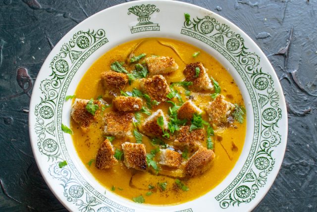 Наливаем морковный суп-пюре с сыром в тарелку. Посыпаем золотистыми гренками и мелко нарезанной петрушкой.