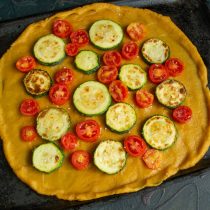 Кладём на тесто обжаренные ломтики кабачка и кружочки помидоров. Кладём на тесто обжаренные ломтики кабачка и кружочки помидоров.