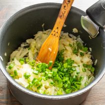 Зеленый лук нарезаем мелко, бросаем нарезанный лук в тушеную капусту.