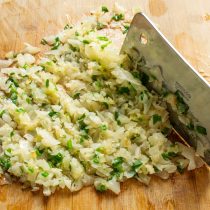 Мясным топориком или широким острым ножом рубим капусту несколько минут.