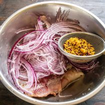 Кладем нарезанную сельдь и красный лук в миску.