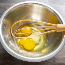 Разбиваем в миску куриные яйца, насыпаем щепотку соли.