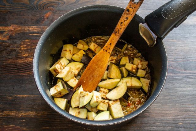 Нарезаем баклажаны кубиками и добавляем их в сотейник к луку. Нарезаем баклажаны кубиками и добавляем их в сотейник к луку.