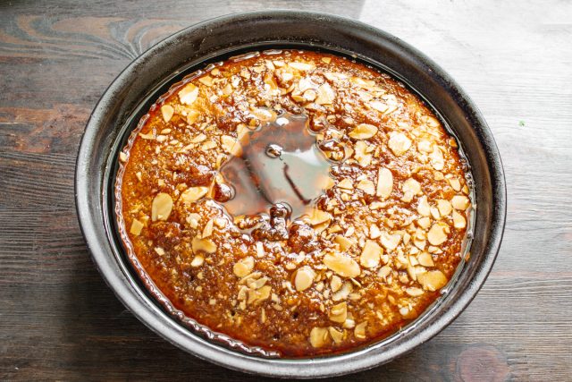 Часто протыкаем горячий пирог деревянной шпажкой по всей поверхности. Равномерно заливаем манник горячим сиропом,