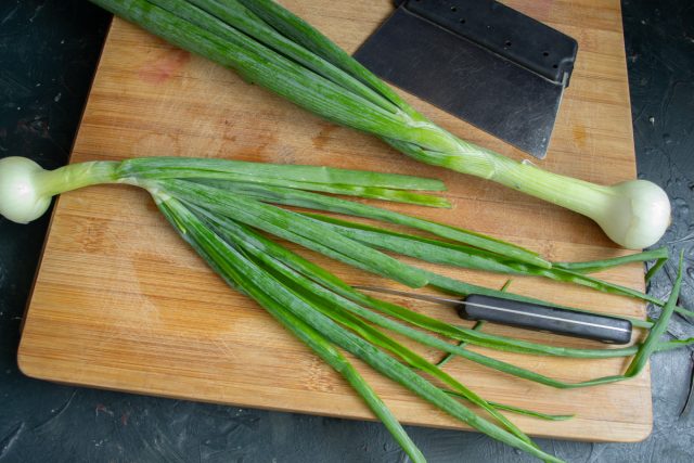 Разрезаем перья зеленого лука вдоль пополам и тщательно промываем их под струей холодной воды. Этот способ позволяет удалить скрытые загрязнения внутри. Разрезаем перья зеленого лука вдоль пополам и тщательно промываем их под струей холодной воды. Этот способ позволяет удалить скрытые загрязнения внутри.