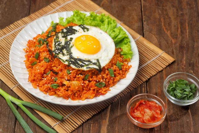 Корейский кимчи-бокеумбап — жареный рис с хорошо ферментированным кимчи, которое при обжарке карамелизуется и становится глубже по вкусу. Кислинка, умеренная острота и ореховый аромат кунжутного масла делают блюдо ярким и узнаваемым.