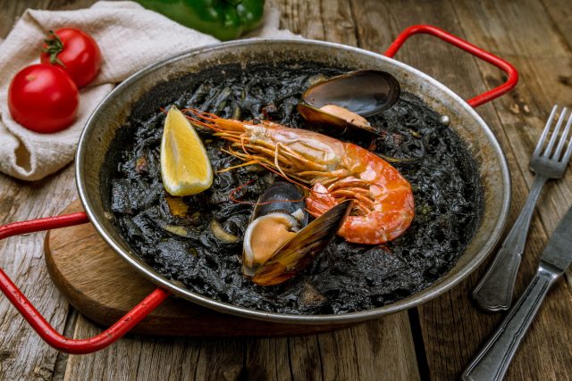 Каталонский аррос негро — вариация паэльи с чернилами каракатицы, придающими рису чёрный цвет и выраженный морской вкус. Подаётся с айоли, чья кремовость смягчает солоноватый умами-фон.