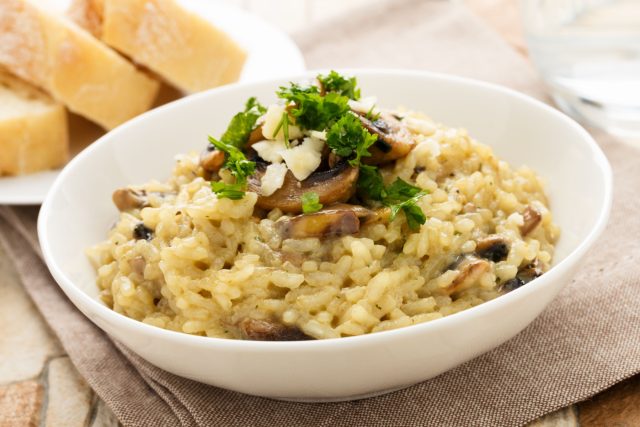 Североитальянское ризотто готовят с постепенным добавлением бульона, чтобы рис выделил крахмал и стал кремовым. Правильная текстура — «волной», мягкая и обволакивающая, без излишней плотности.