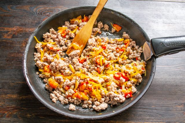 Перекладываем обжаренный фарш в сковороду с готовыми овощами. Тщательно перемешиваем ингредиенты лопаткой для равномерного распределения начинки.