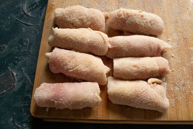 Плотно сворачиваем куриное филе с начинкой в аккуратные рулетики, прячая края. Выкладываем сформированные изделия на разделочную доску швом вниз.
