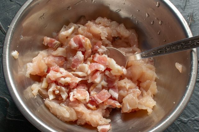 Мелко нарезаем сырокопченый бекон ножом. Соединяем измельченный бекон с подготовленным куриным фаршем в глубокой миске для создания основы начинки.