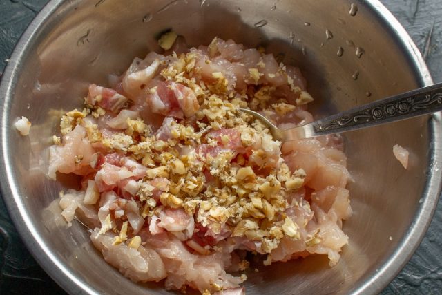 Рубим ядра грецких орехов ножом на мелкие кусочки, избегая превращения их в пыль. Добавляем измельченные орехи в миску к куриному фаршу и бекону.