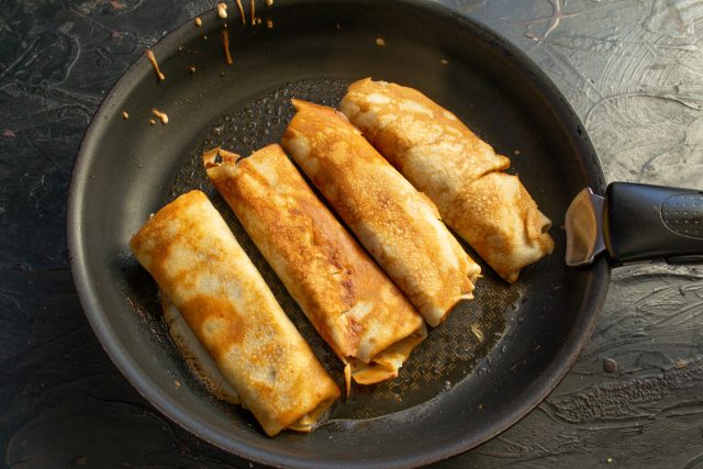 Растапливаем щедрый кусок сливочного масла в широкой сковороде. Обжариваем свернутые трубочки с обеих сторон до появления хрустящей золотистой корочки. Растапливаем щедрый кусок сливочного масла в широкой сковороде. Обжариваем свернутые трубочки с обеих сторон до появления хрустящей золотистой корочки.